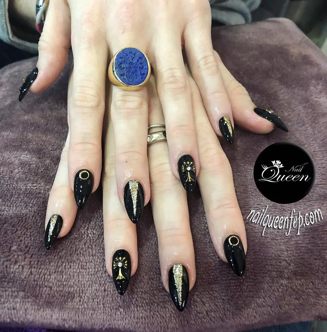 Glossy black nails with gold glitter stripes and rhinestone accents