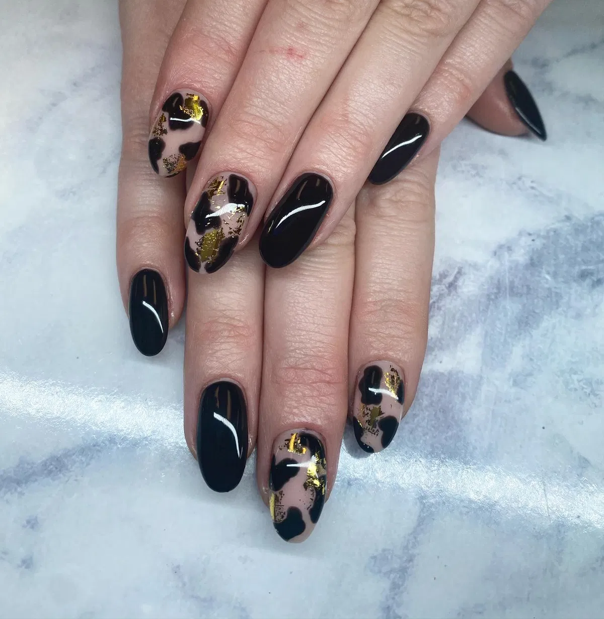 Glossy black nails with gold-flecked abstract accents