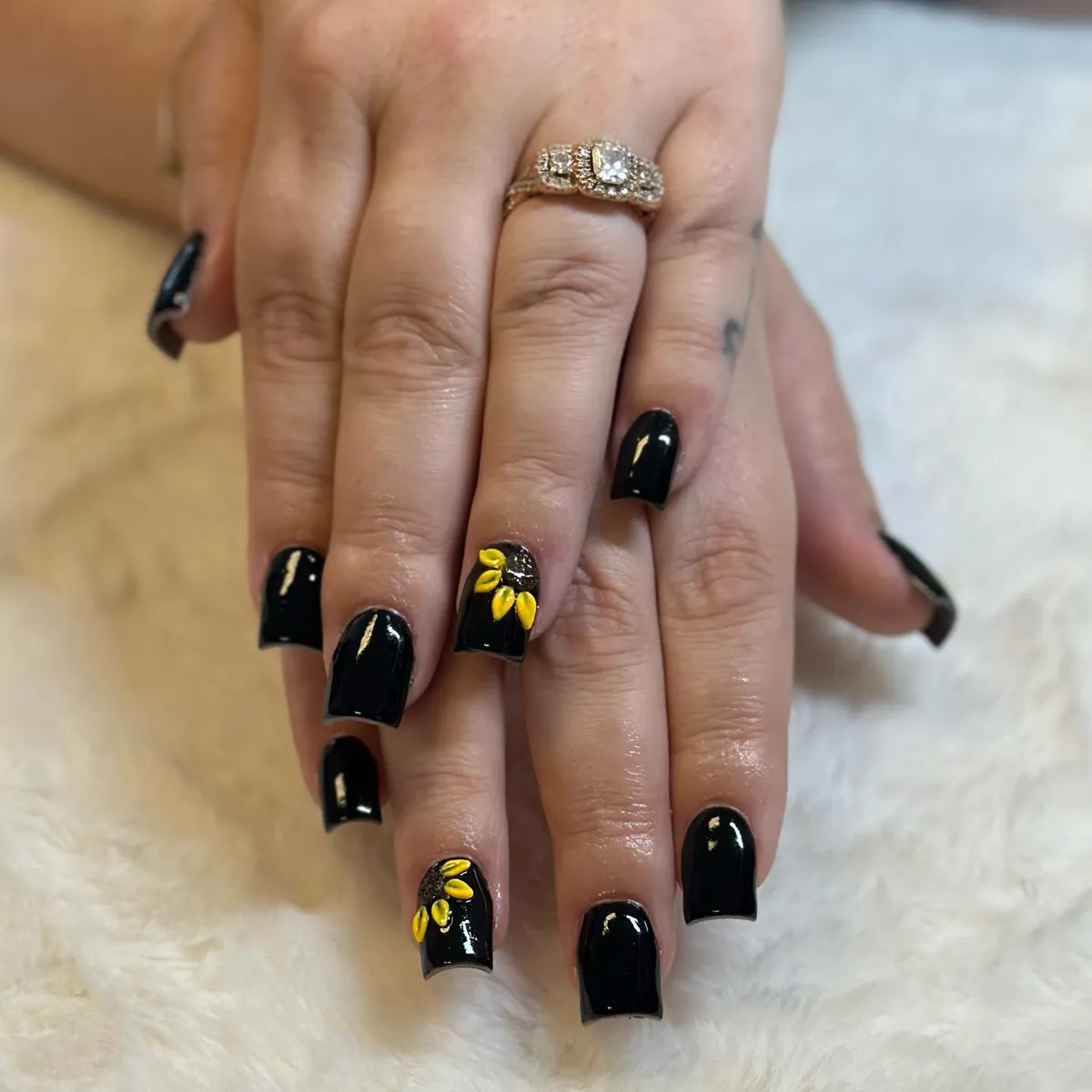 Glossy black nails with small raised yellow petal accents