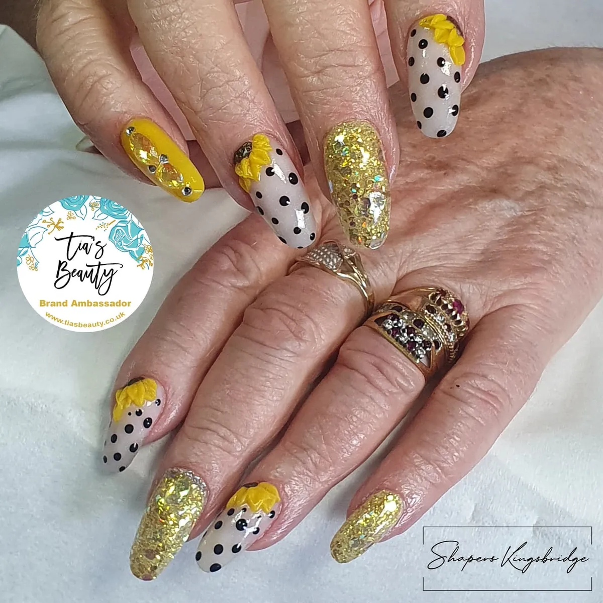 Gold glitter and polka-dot nude nails with raised yellow petal accents