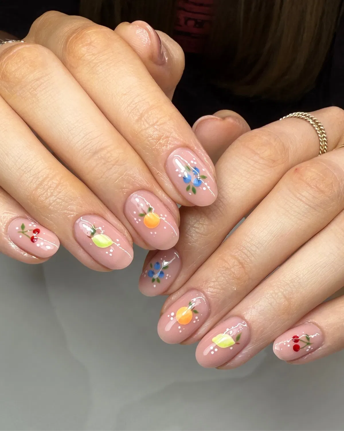 Tiny fruit illustrations on glossy pale pink nails
