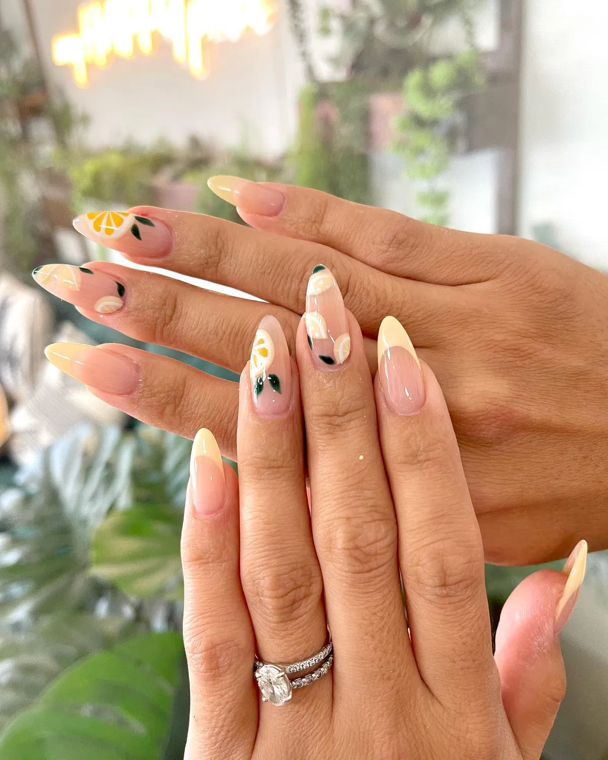 Sheer nude almond nails with pale yellow tips and small citrus accents