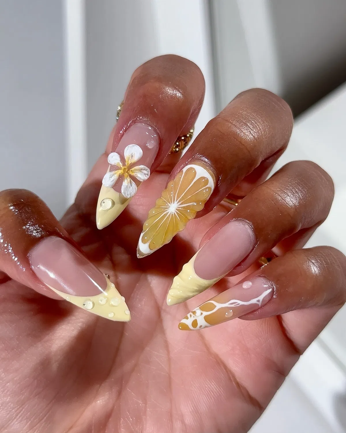 Stiletto pale-yellow tips with 3D flower and citrus-slice accent