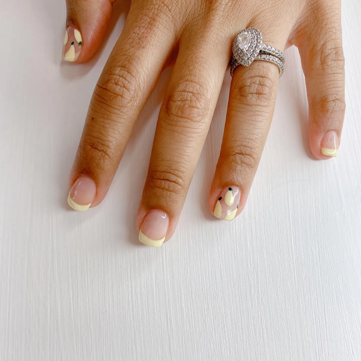 Short pale-yellow French tips with abstract accent nail