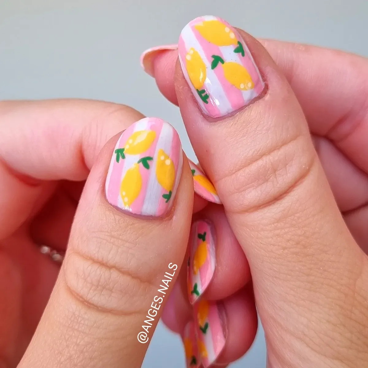 Pink-and-white striped nails with repeating lemon pattern