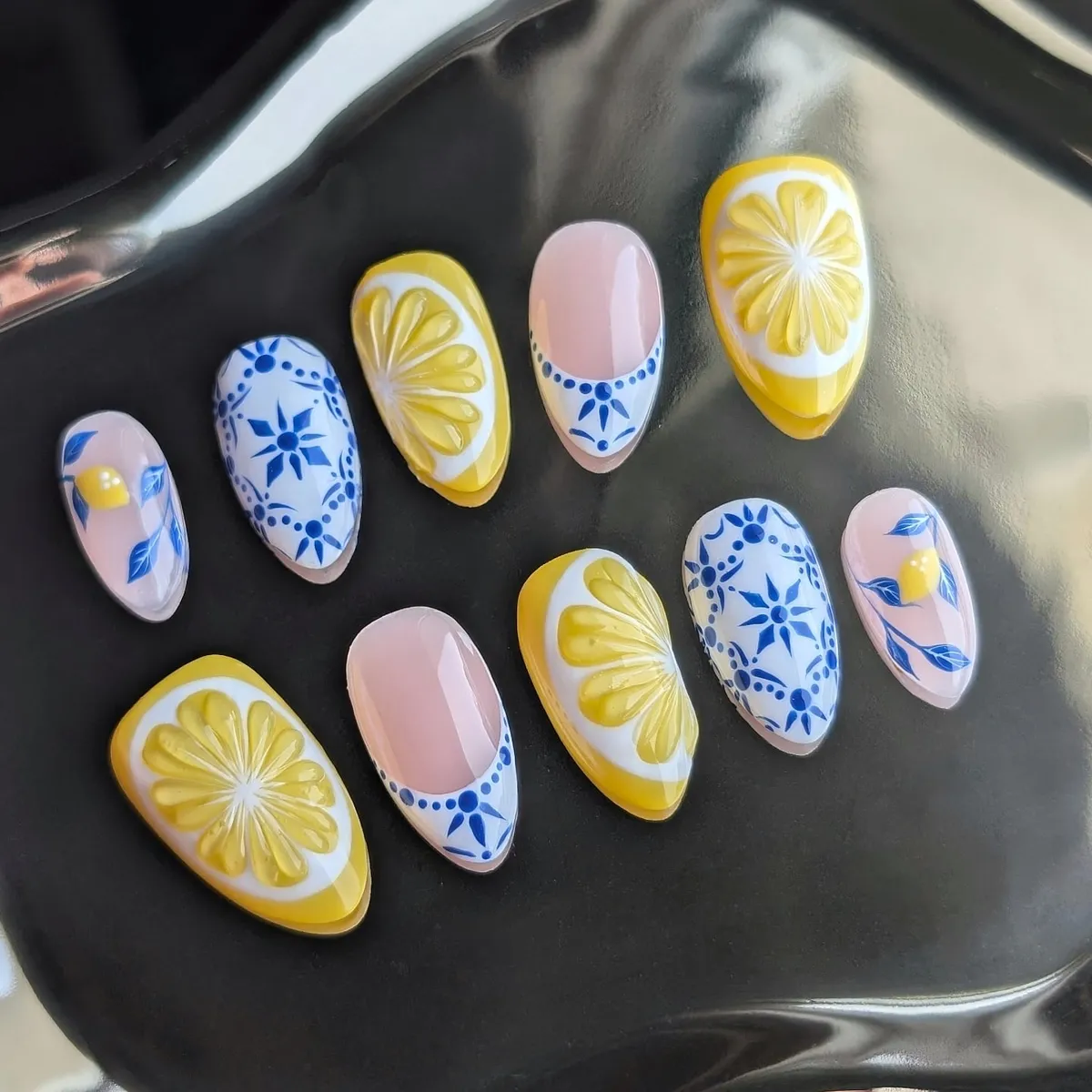 Displayed nail tips with lemon slices and blue floral motifs