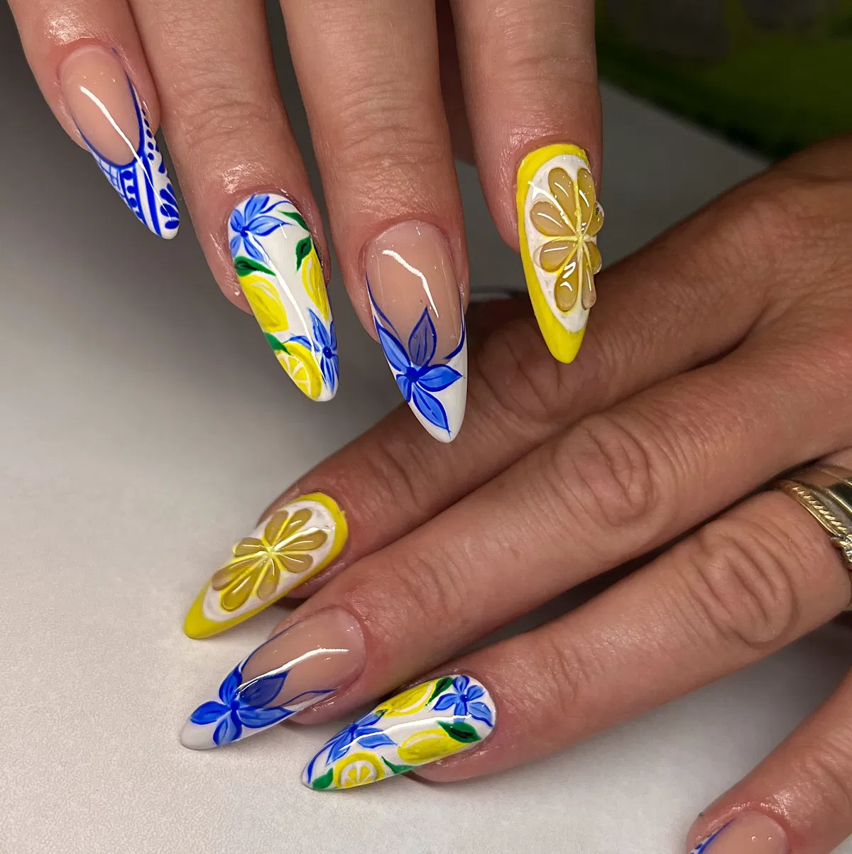 Stiletto lemon nails with blue-and-white tile-style patterns