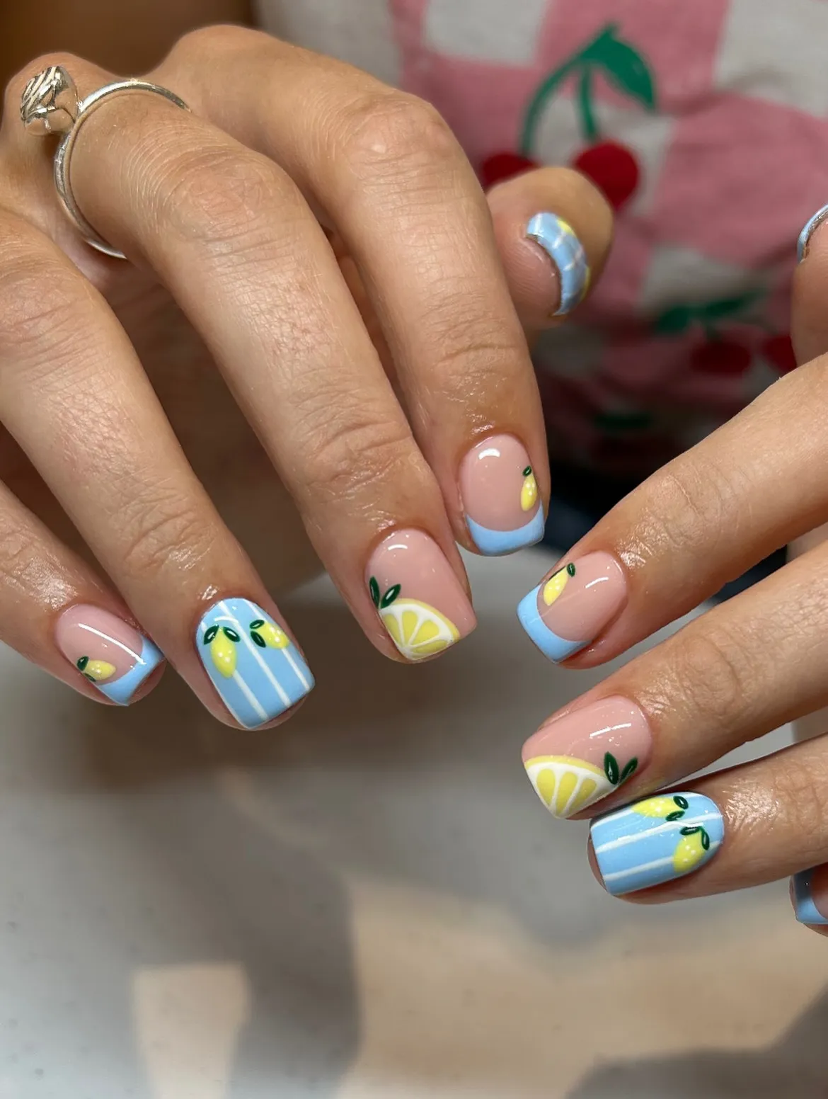 Short nude nails with light-blue tips and lemon accents