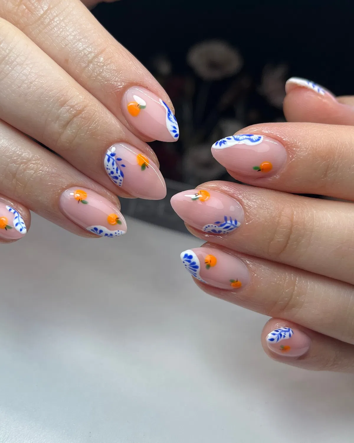 Nude base with blue corner detailing and tiny orange fruit motifs
