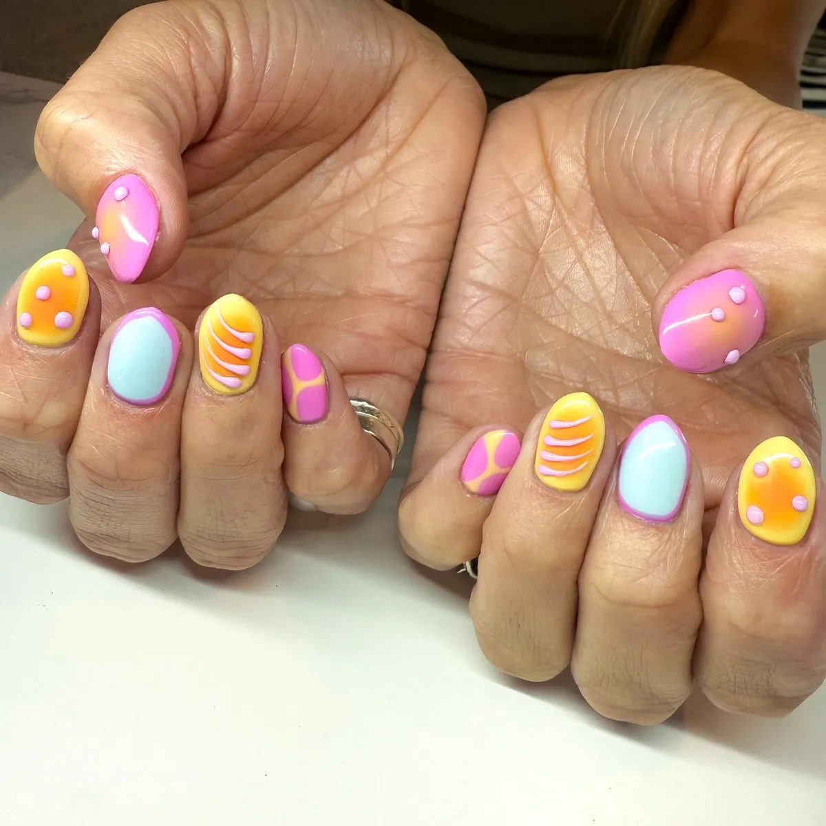 Bright pastel nails with raised dots and curved stripes