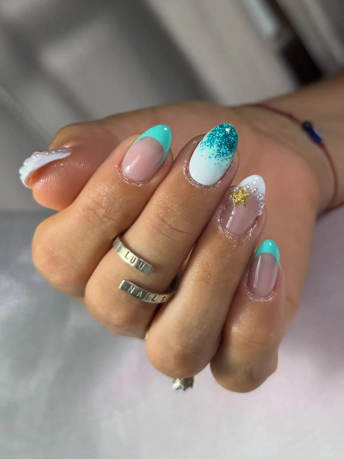 Turquoise French tips with sparkle fade and a gold star charm accent