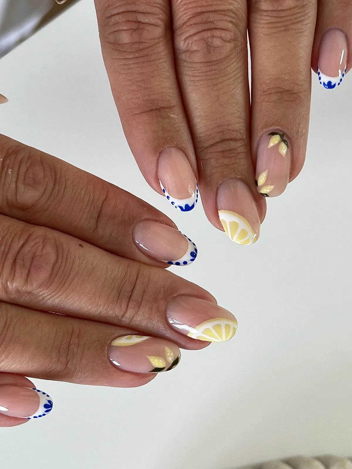 Nude base with blue-dotted French tips and citrus wedges