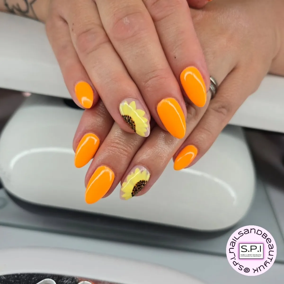 Glossy orange nails with pale yellow floral accent nails