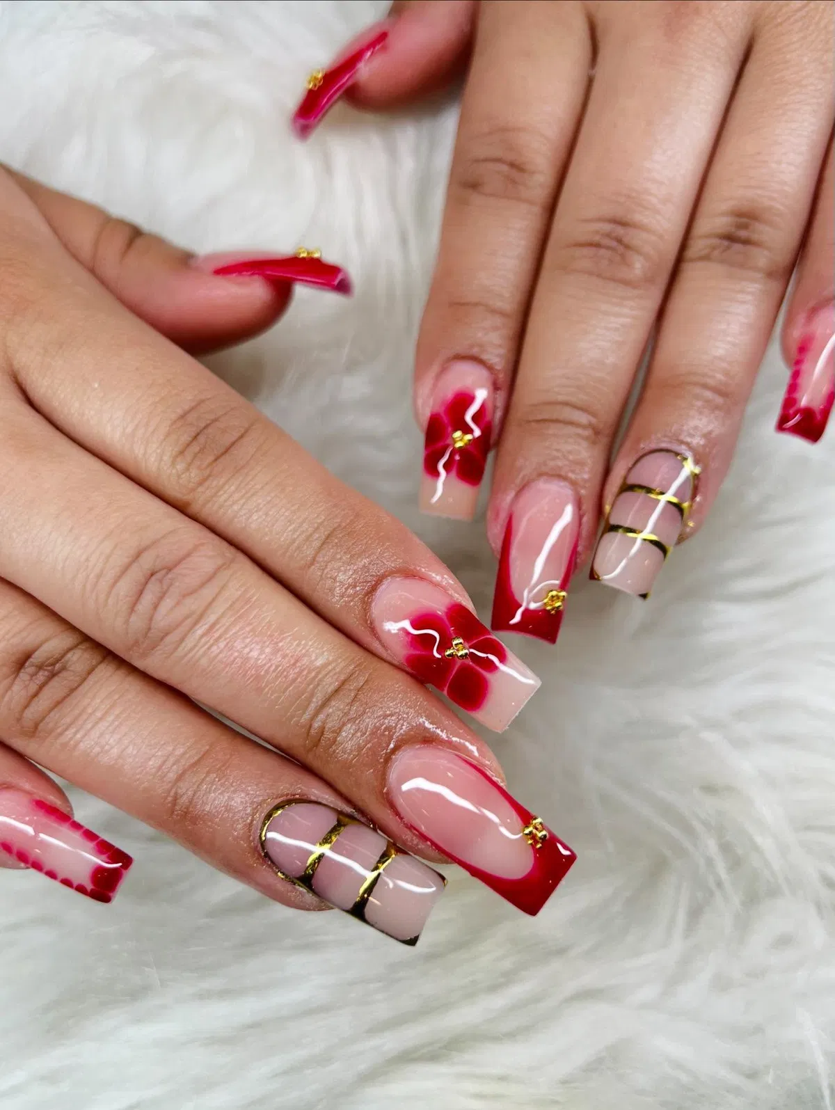 Long red French tips with gold striping and floral accents