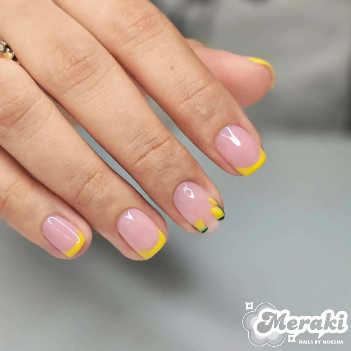 Light pink base with yellow French tips and a tiny lemon accent