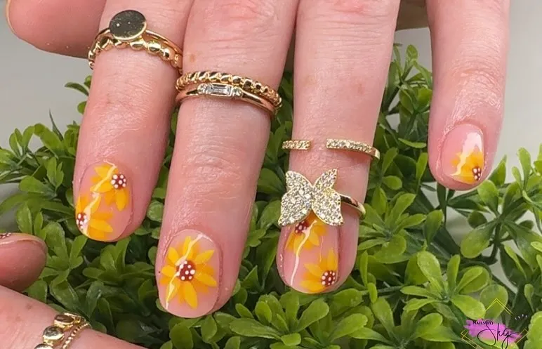Nude nails with orange-yellow flowers and white dot centers