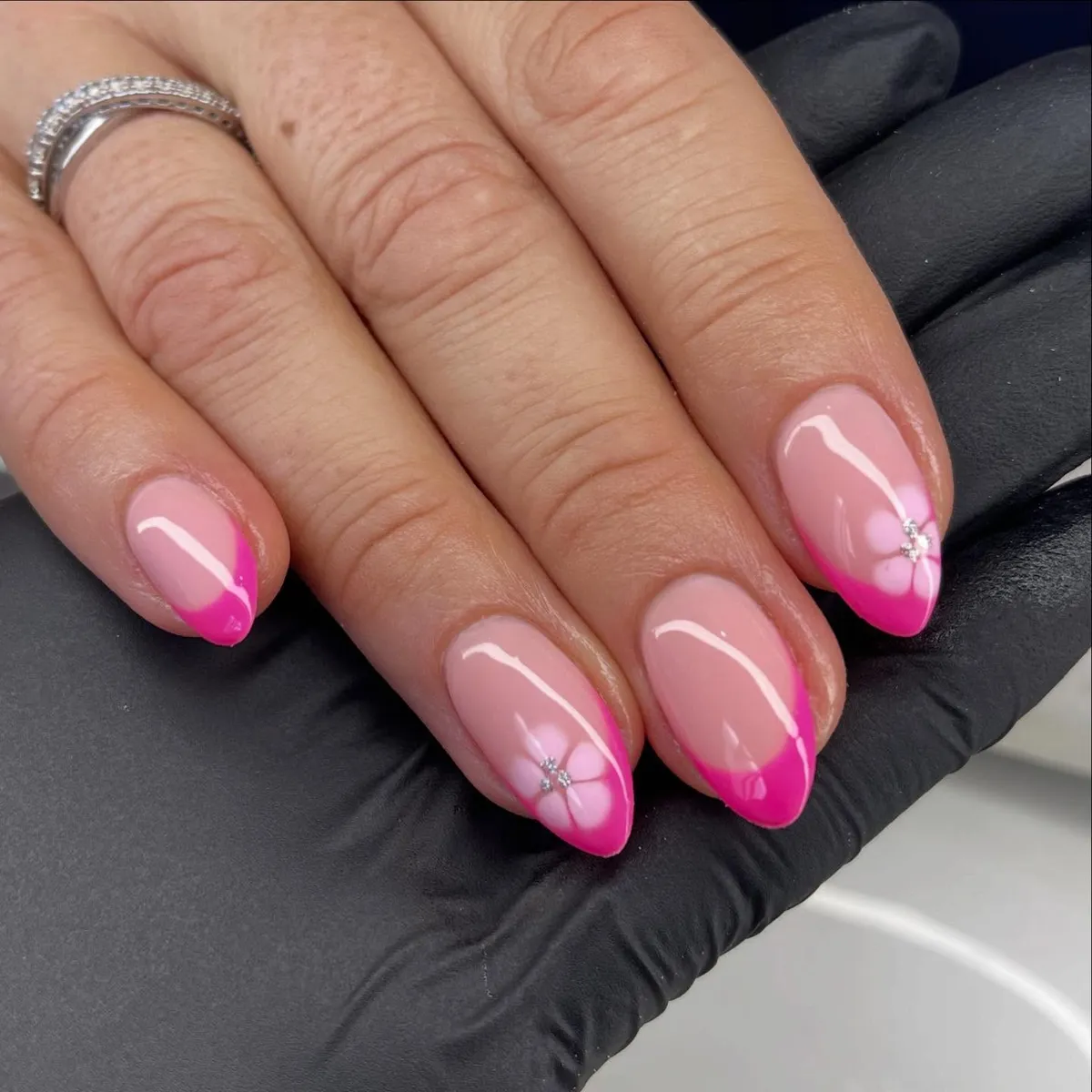 Hot-pink ombrรฉ French with rhinestone-centered flowers