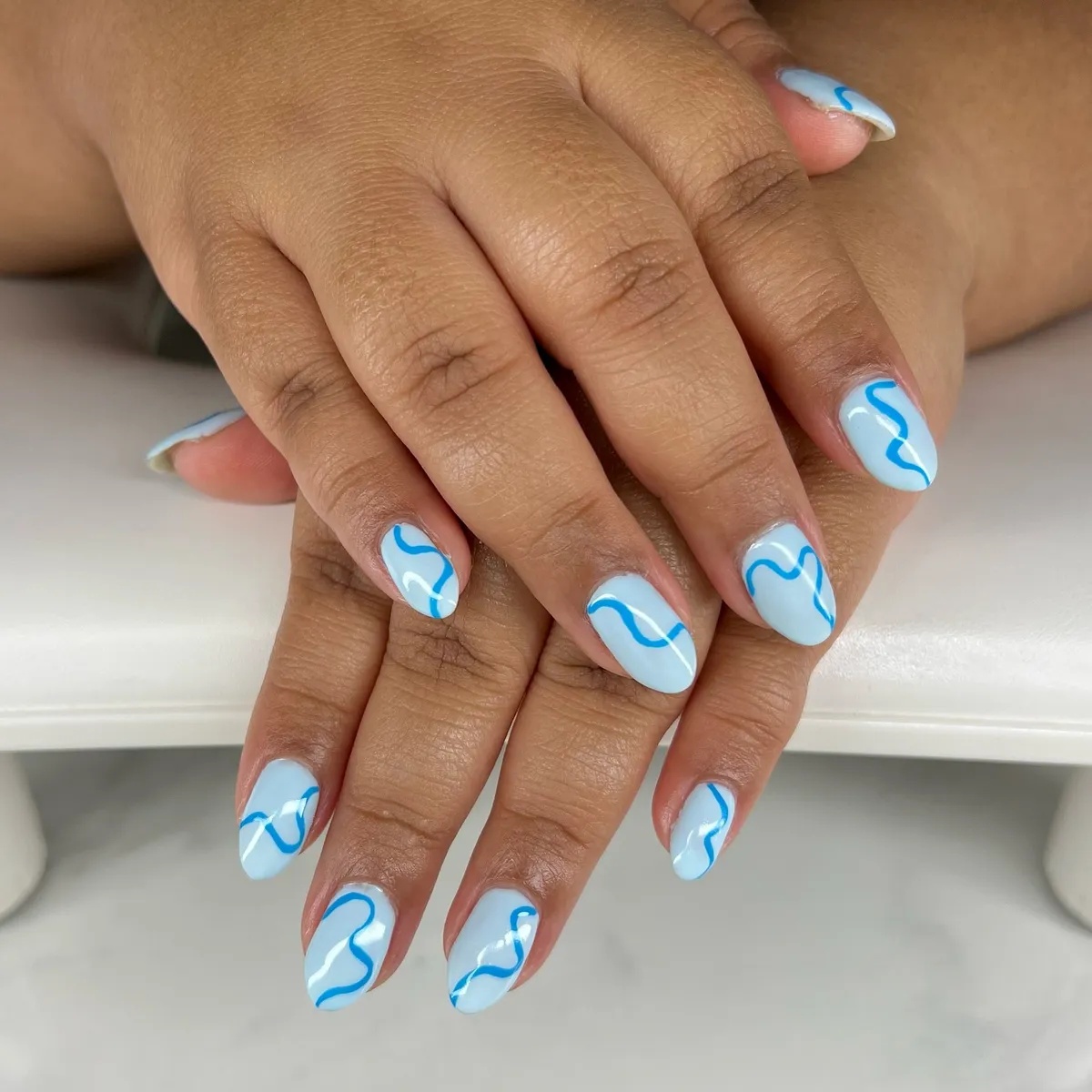 Light blue nails with simple wavy blue lines