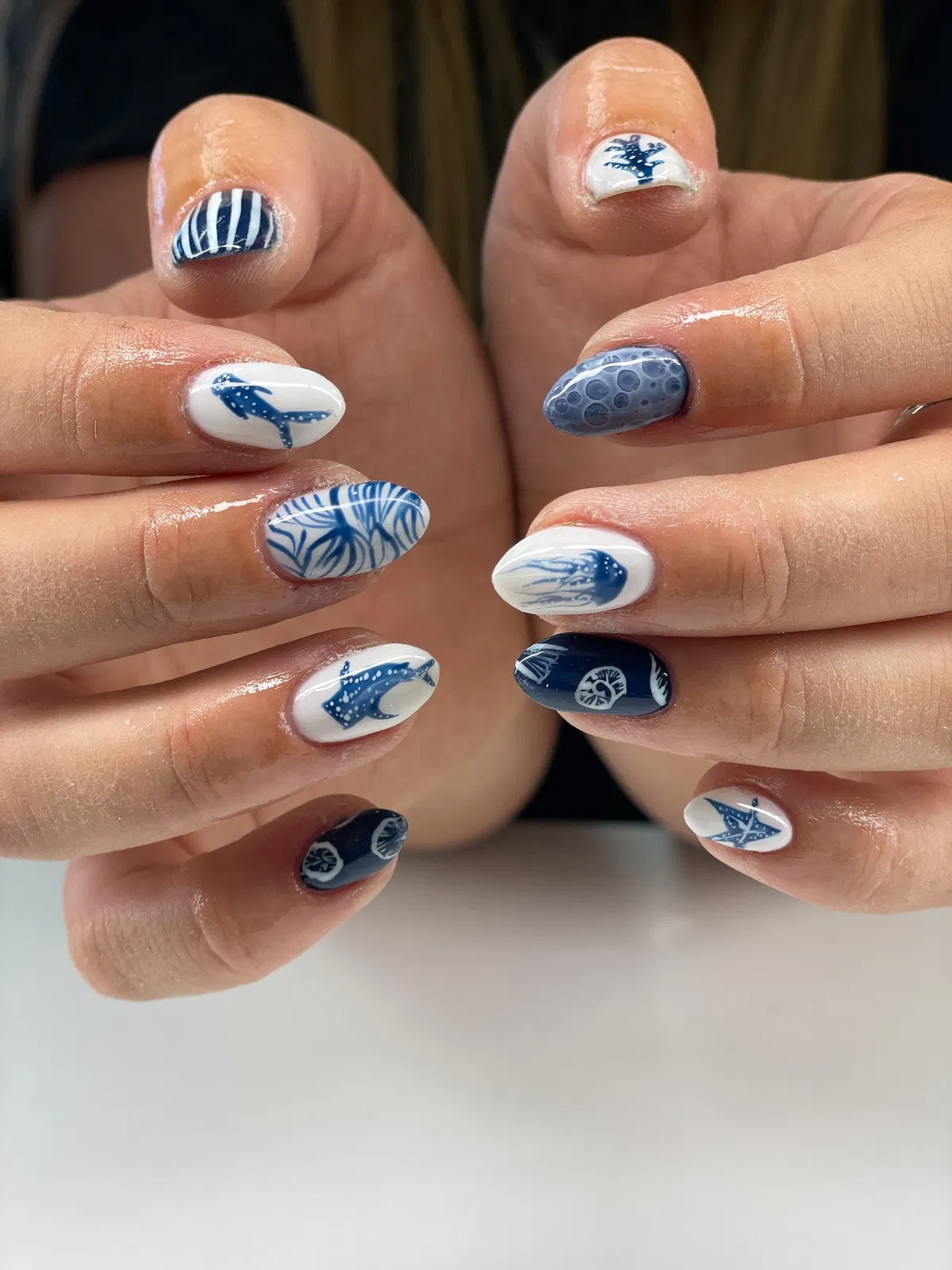 Blue-and-white graphic nail art with stripes and fish-like silhouettes