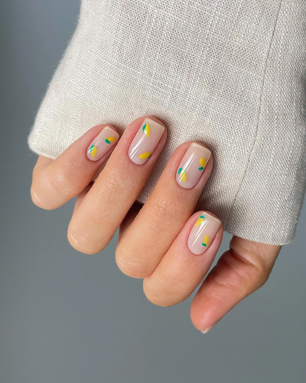 Sheer nude nails with tiny yellow-and-green accents