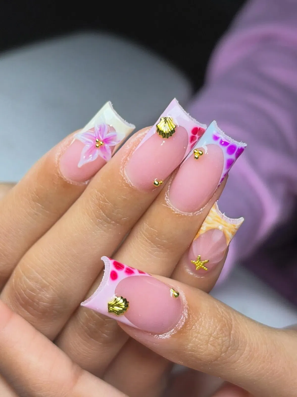 White square tips with colorful patterns and gold-toned charms