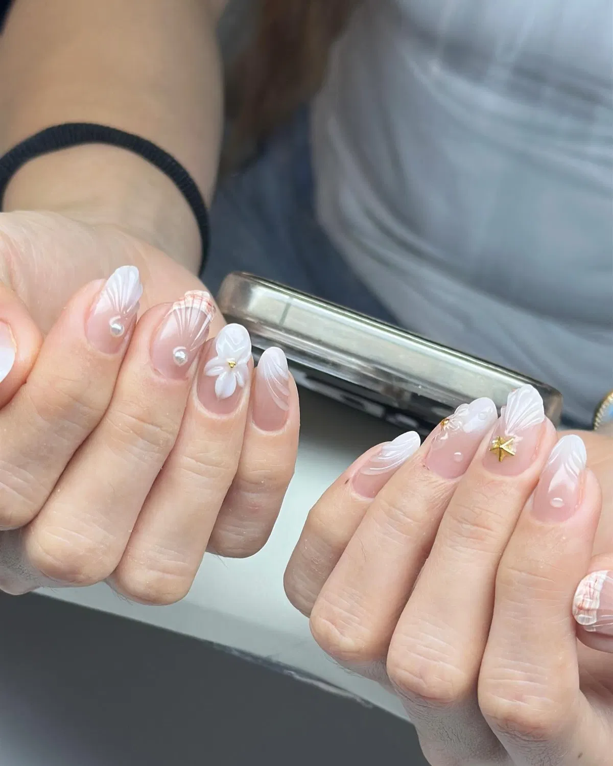 Sheer nude nails with white fan lines, pearls, and a gold star charm