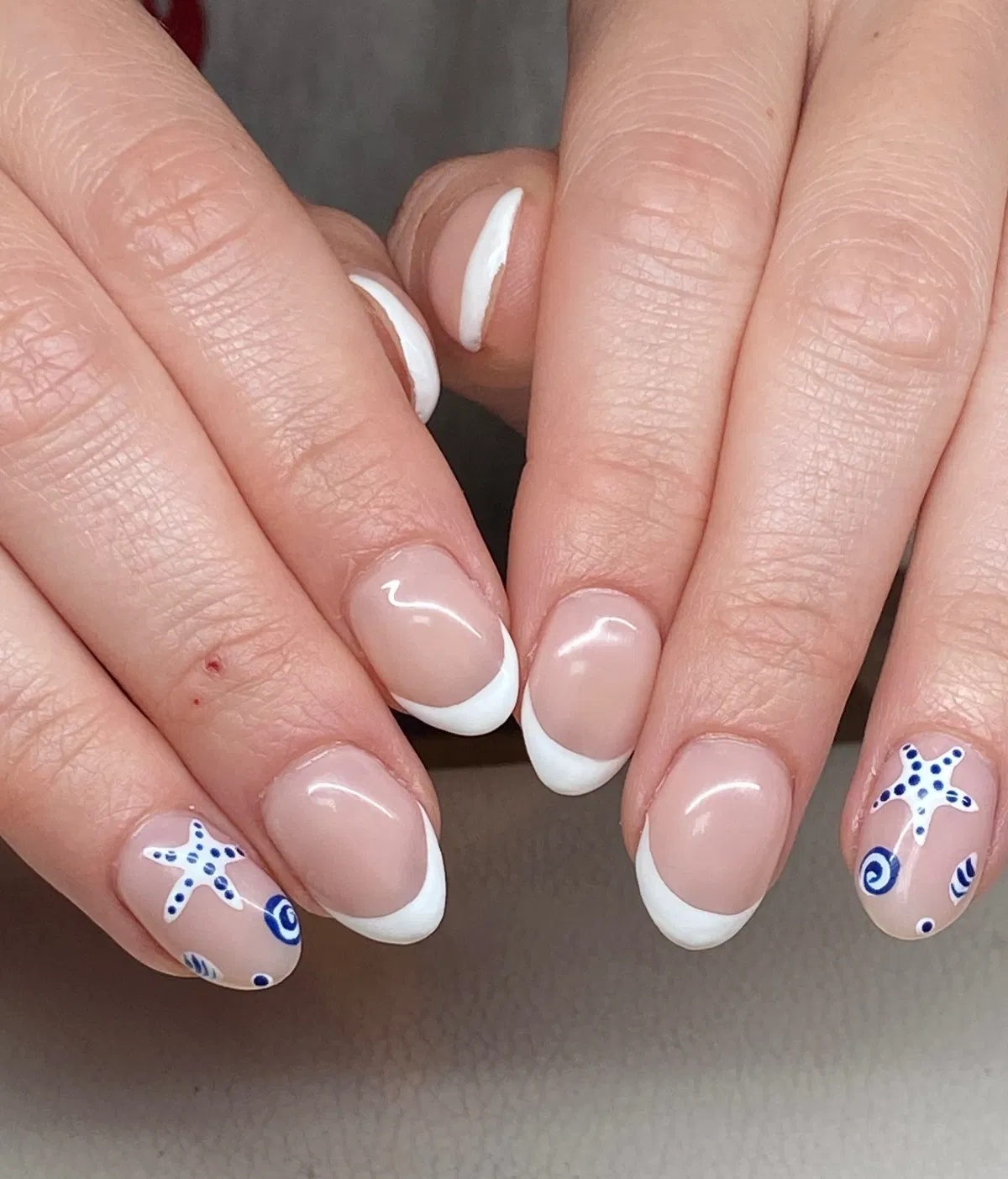 White French tips with blue starfish and swirl accents