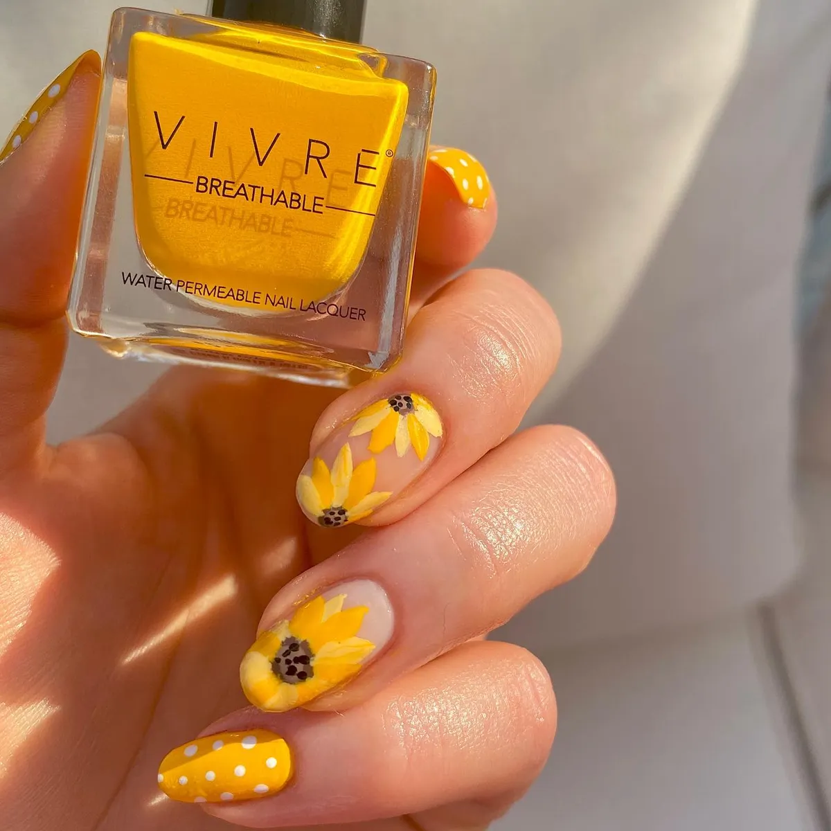 Yellow floral nails with polka dots and lacquer bottle