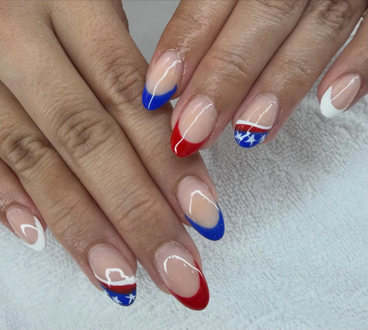 Alternating red/blue French tips with star-banded accent nails
