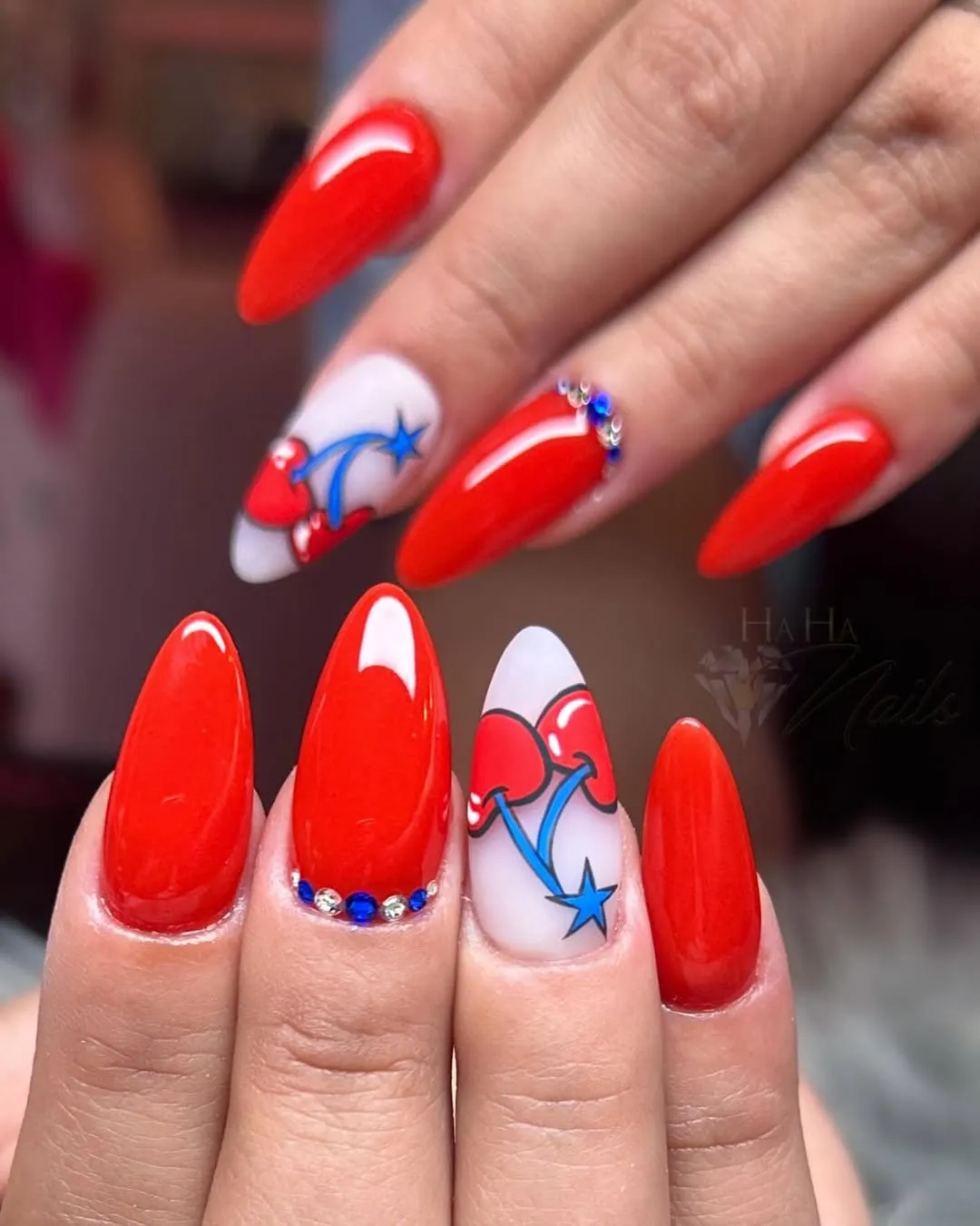 Red almond nails with cherry-and-star accents and rhinestones