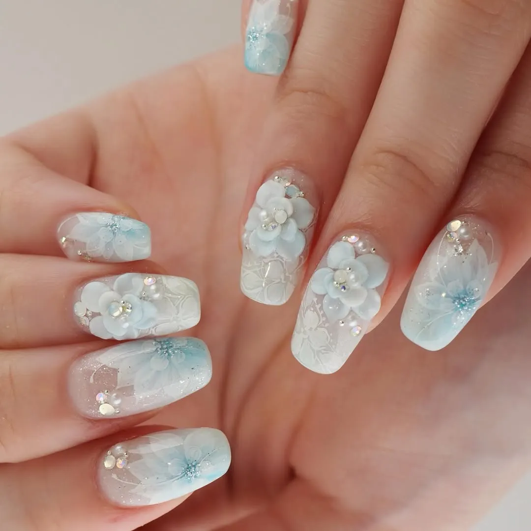 Blue-white gradient square nails with 3D flowers, rhinestones, and lace-like patterns