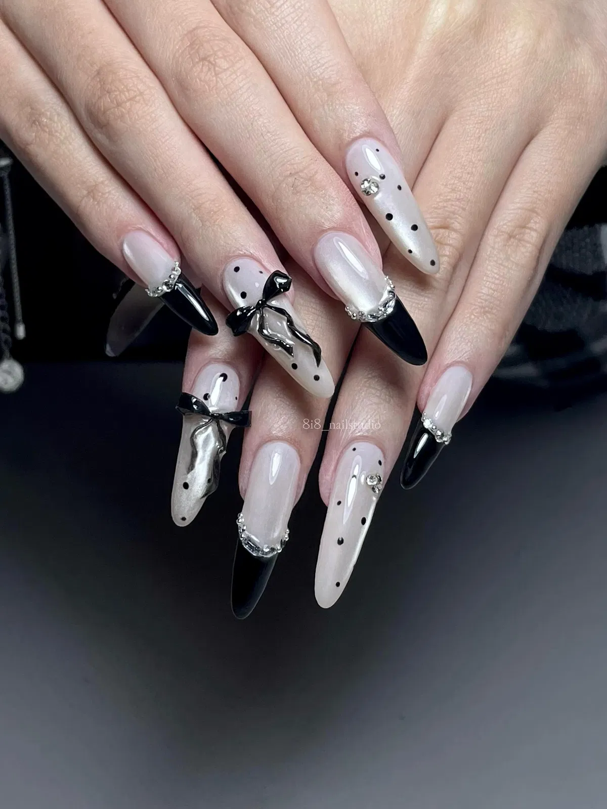 Stiletto black tips with scattered dots, bows, and rhinestone edging