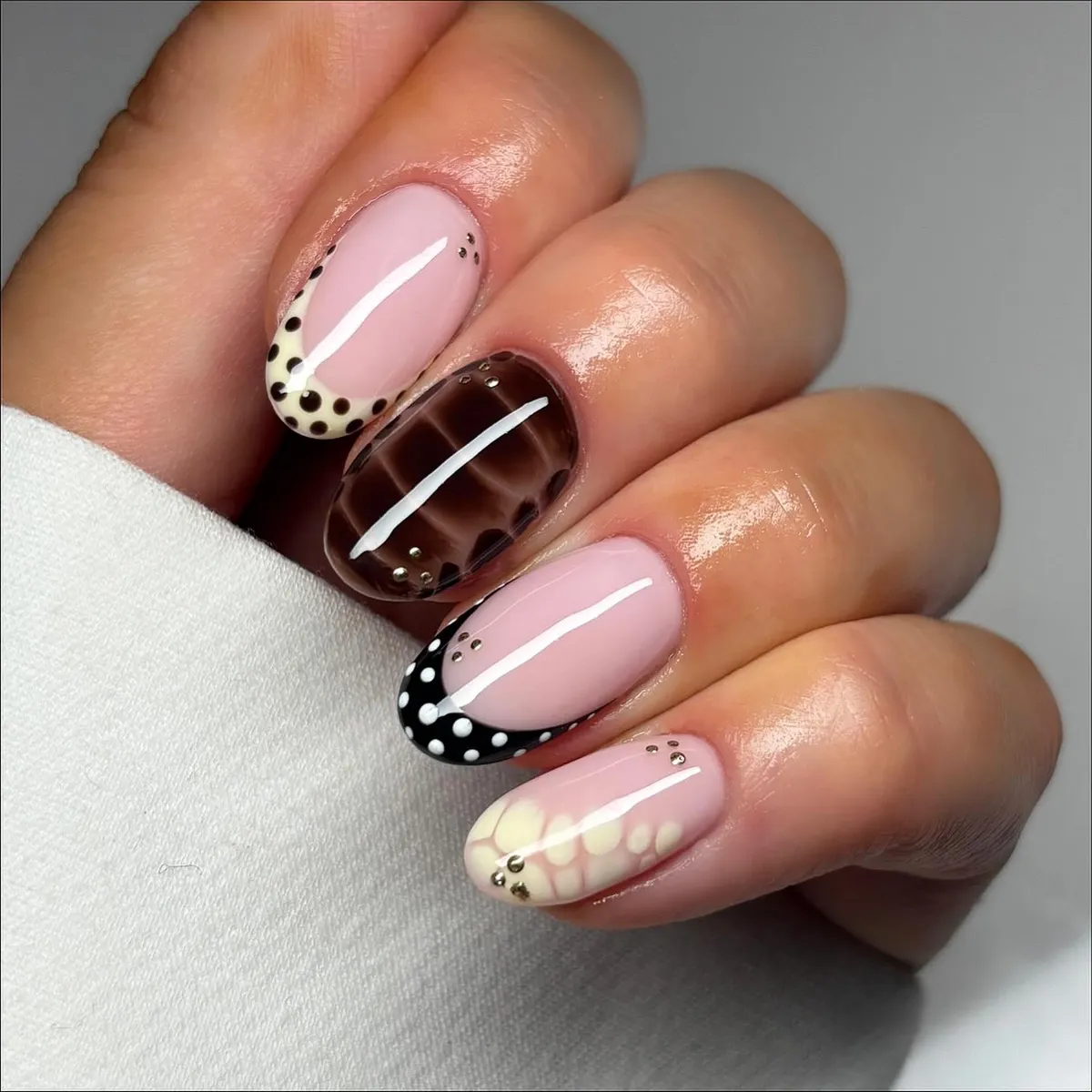 Pale pink set with mixed polka-dot tips and a brown grid accent nail