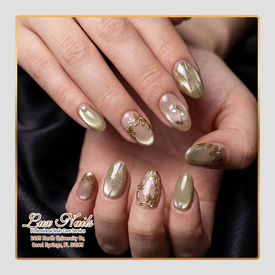 Metallic gold and neutral oval nails with floral decals and pearl-like studs