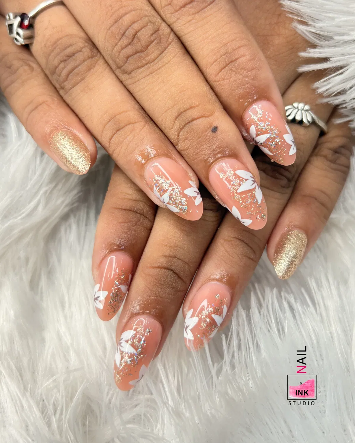 Peach nude nails with white leaf silhouettes and gold glitter accents