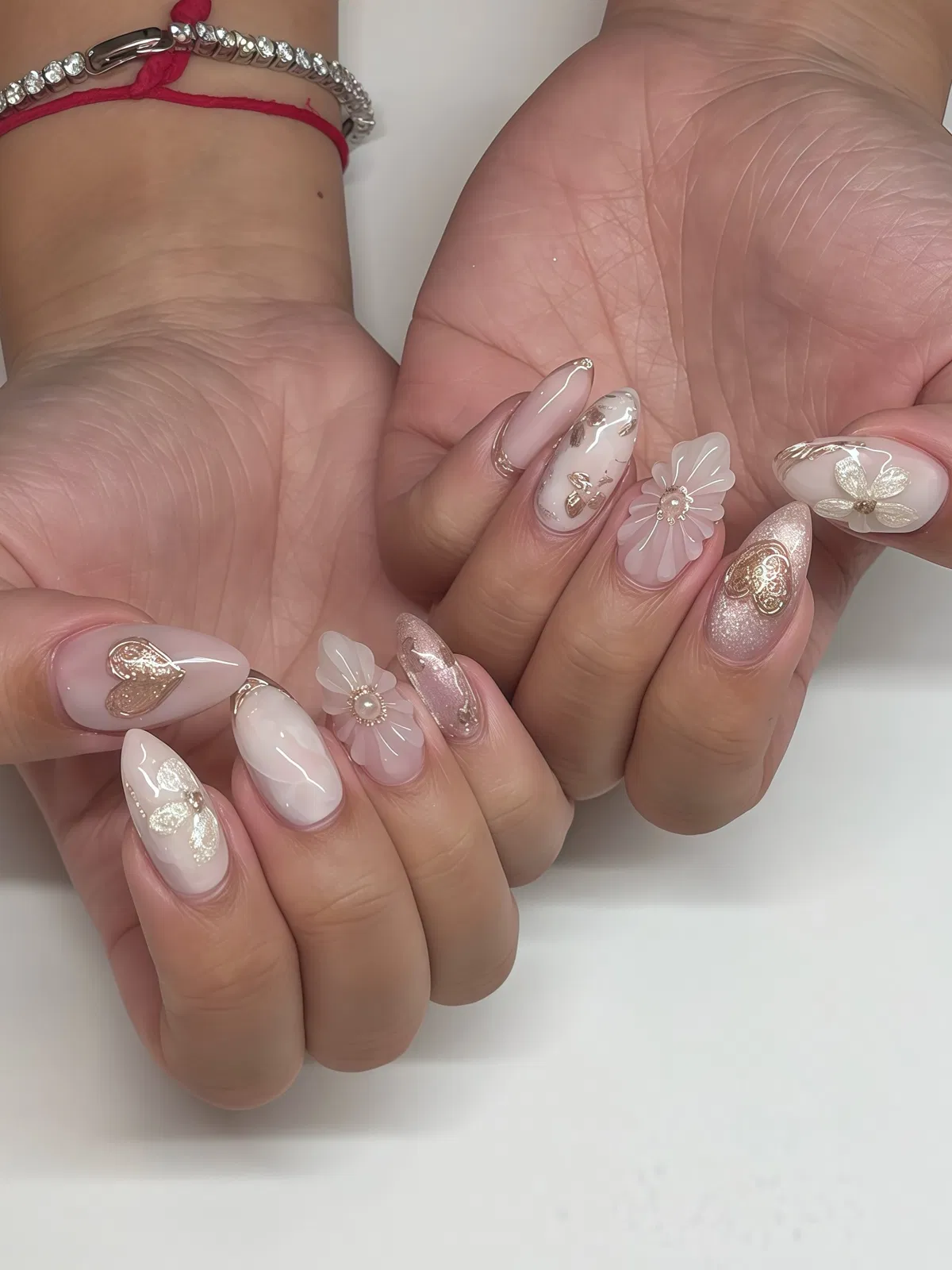 Milky pink-and-white nails with 3D translucent flowers and gold foil accents