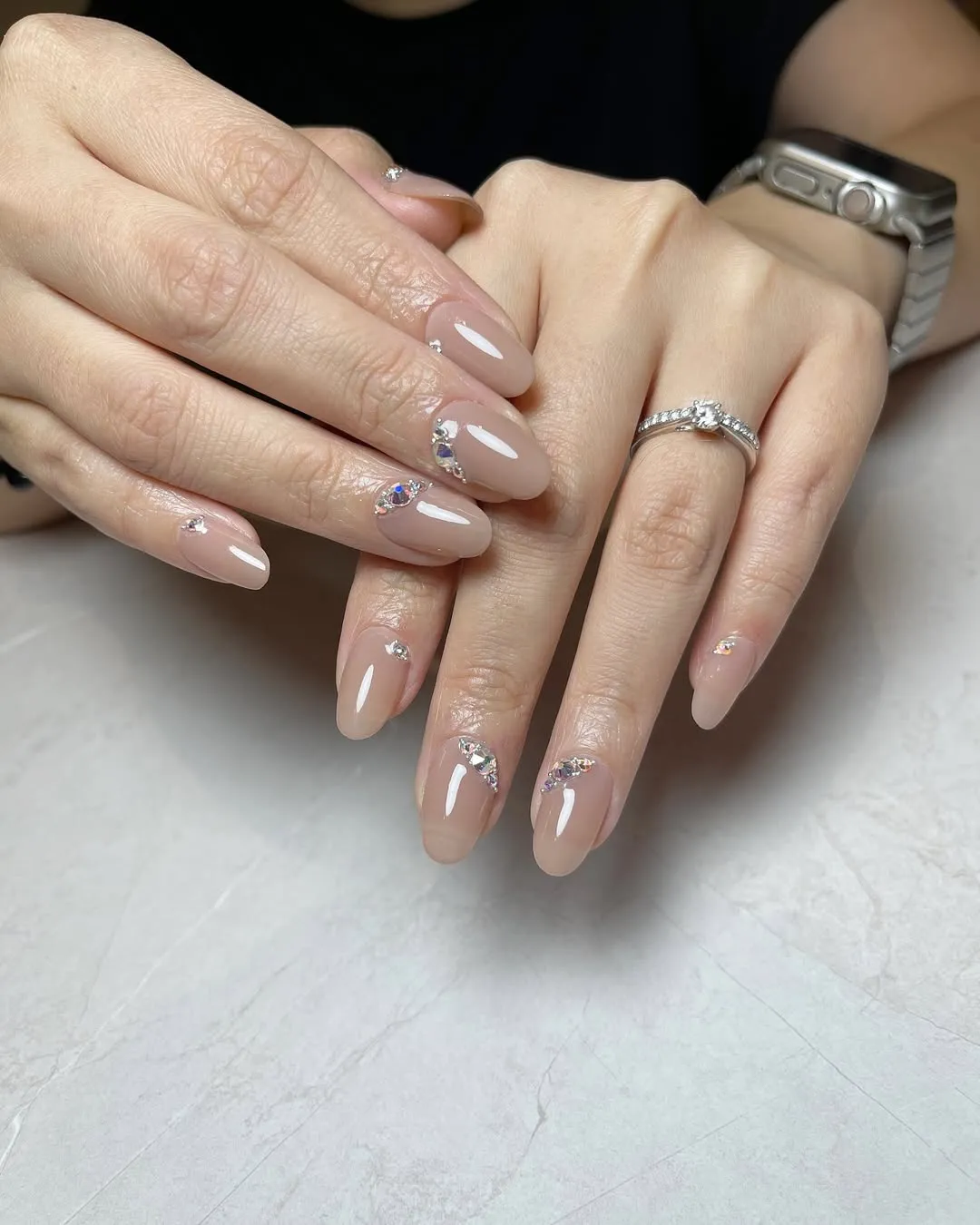 Glossy nude-beige nails with small rhinestone clusters