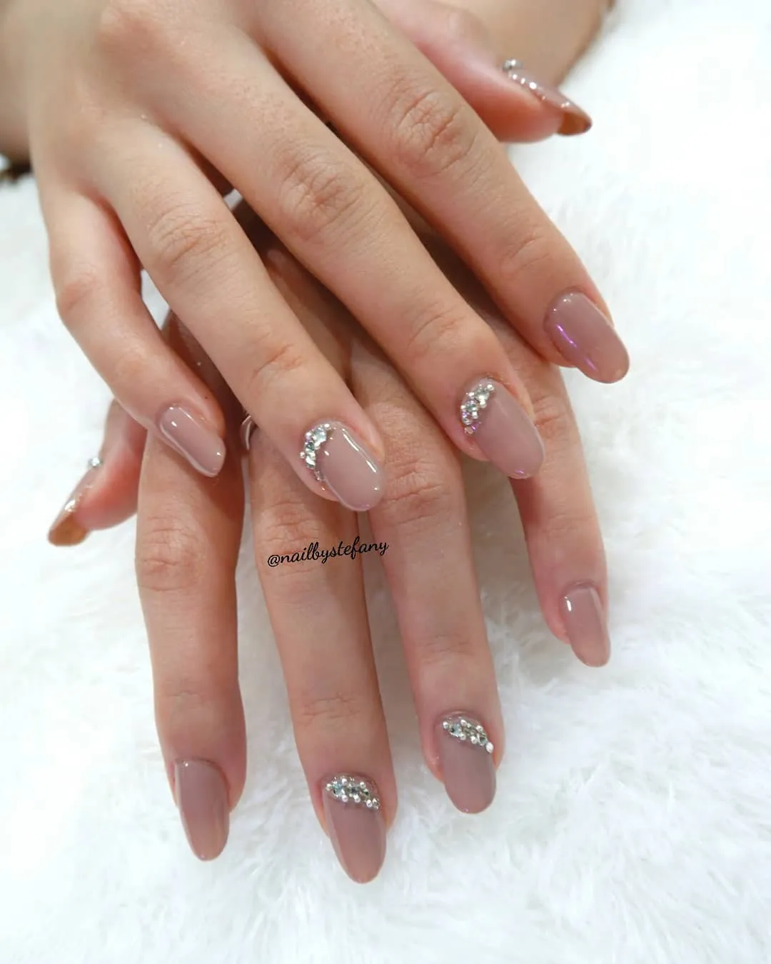 Taupe nude nails with curved rhinestone cuticle accents