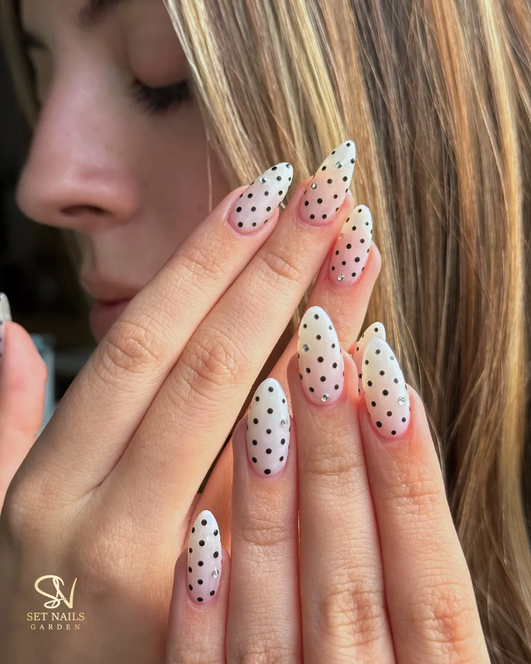 White-gradient nails with black polka dots and small studs