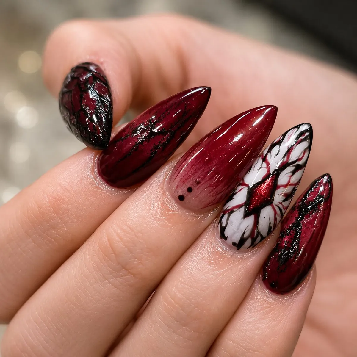 Pointed cherry nails with black crackle detailing and graphic accents