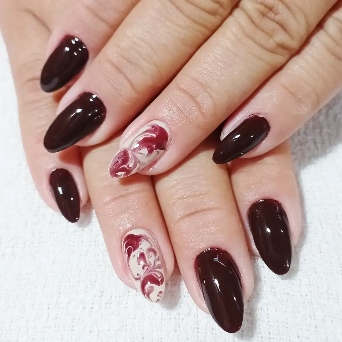 Dark cherry almond nails with red-and-white marbling