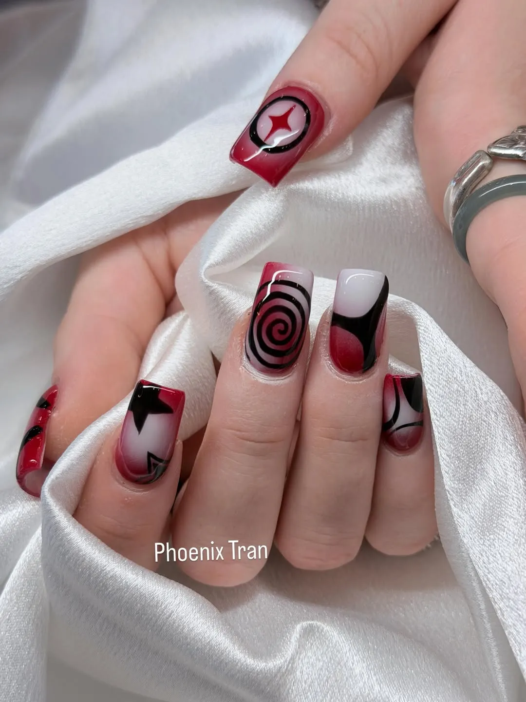 Graphic cherry-and-black nail art with spiral and star motifs