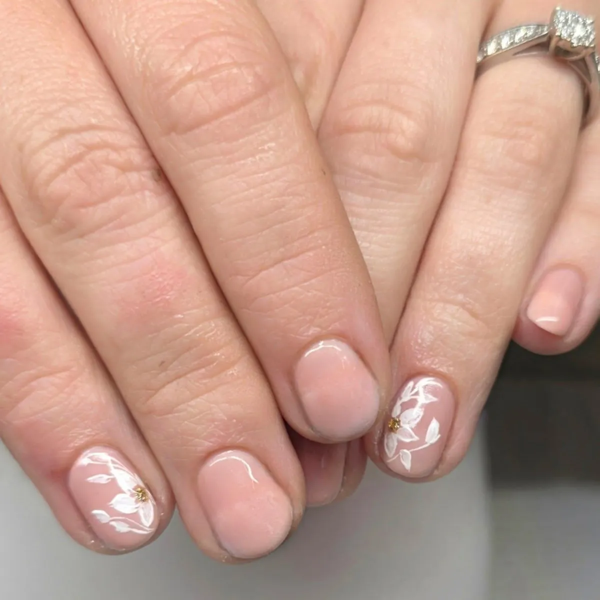 Short nude-pink nails with delicate white floral accents