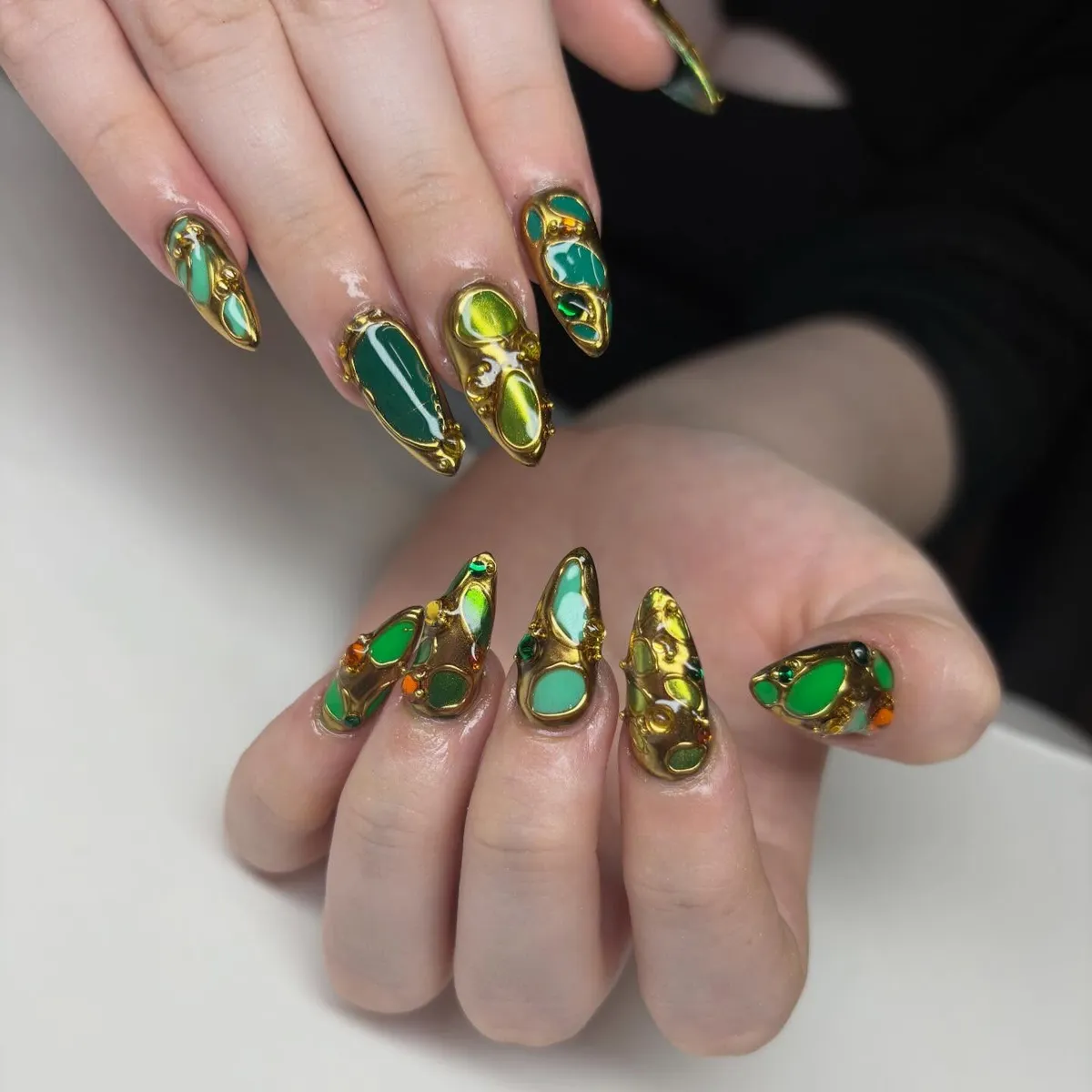 Pointed nails with raised gold framing and green insets