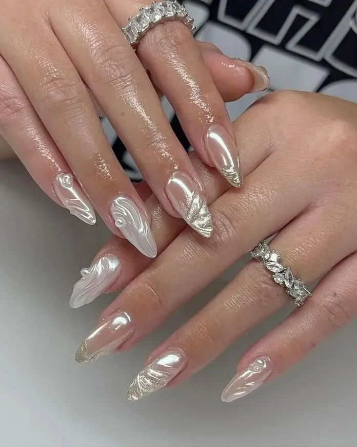 Reflective nude-pink nails with gold-glitter tips and raised swirls