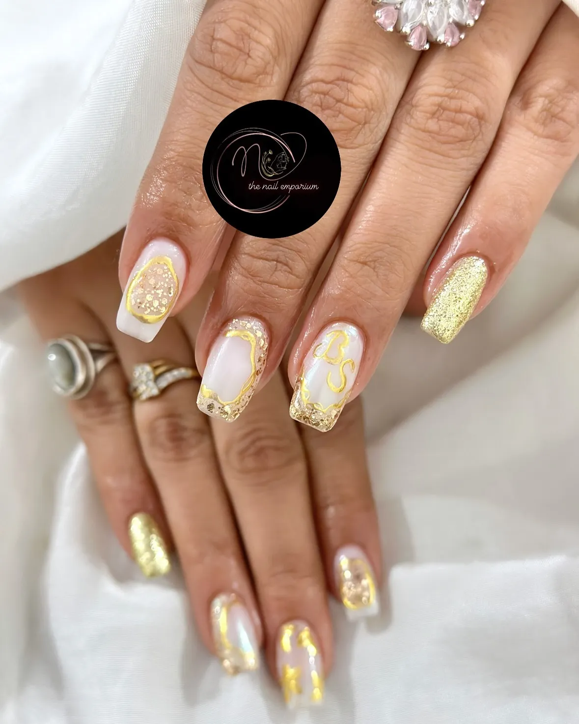 White-and-gold glitter nails with gold outlines and lettering