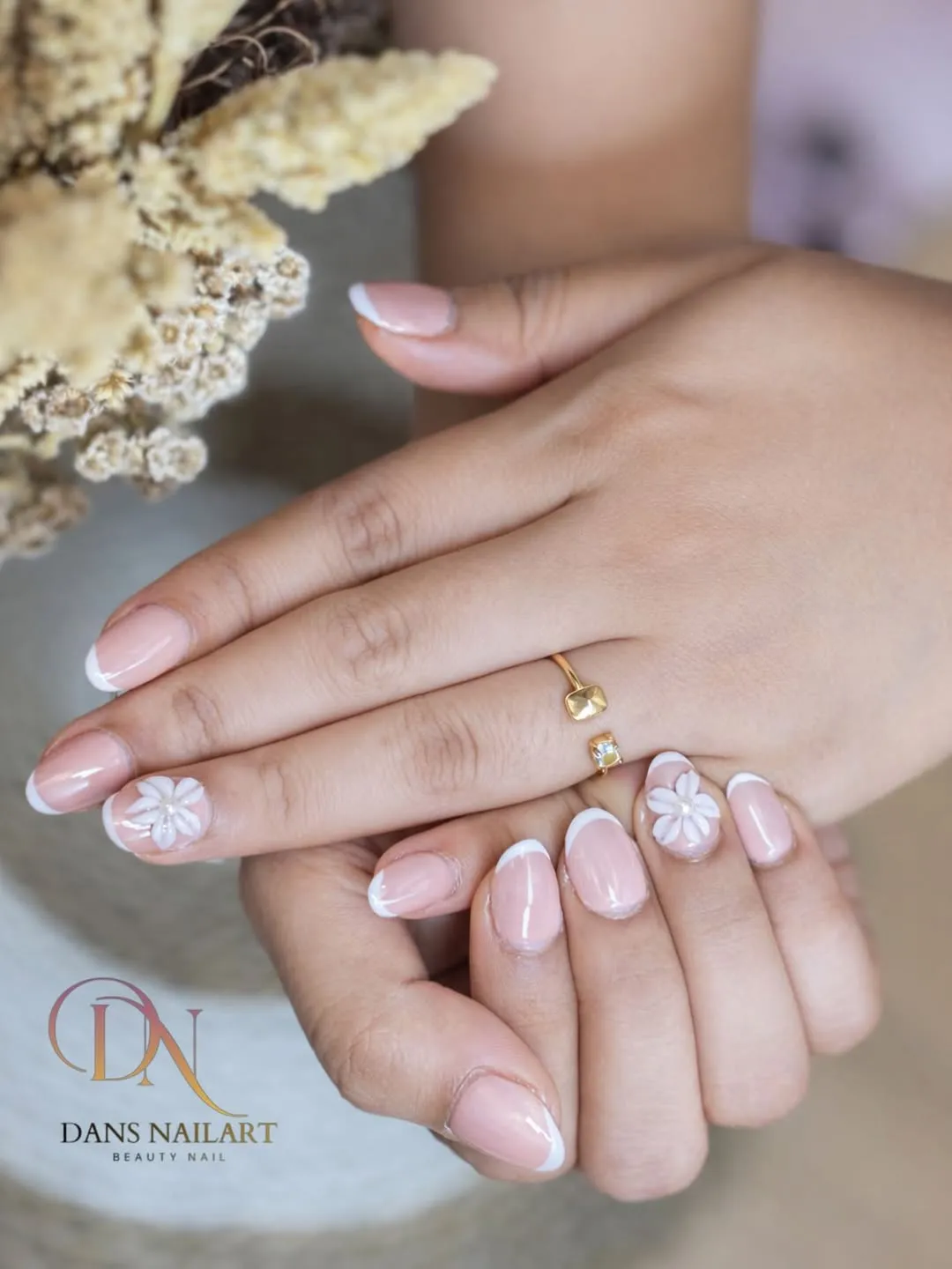 Pale pink French tips with raised white flower accents