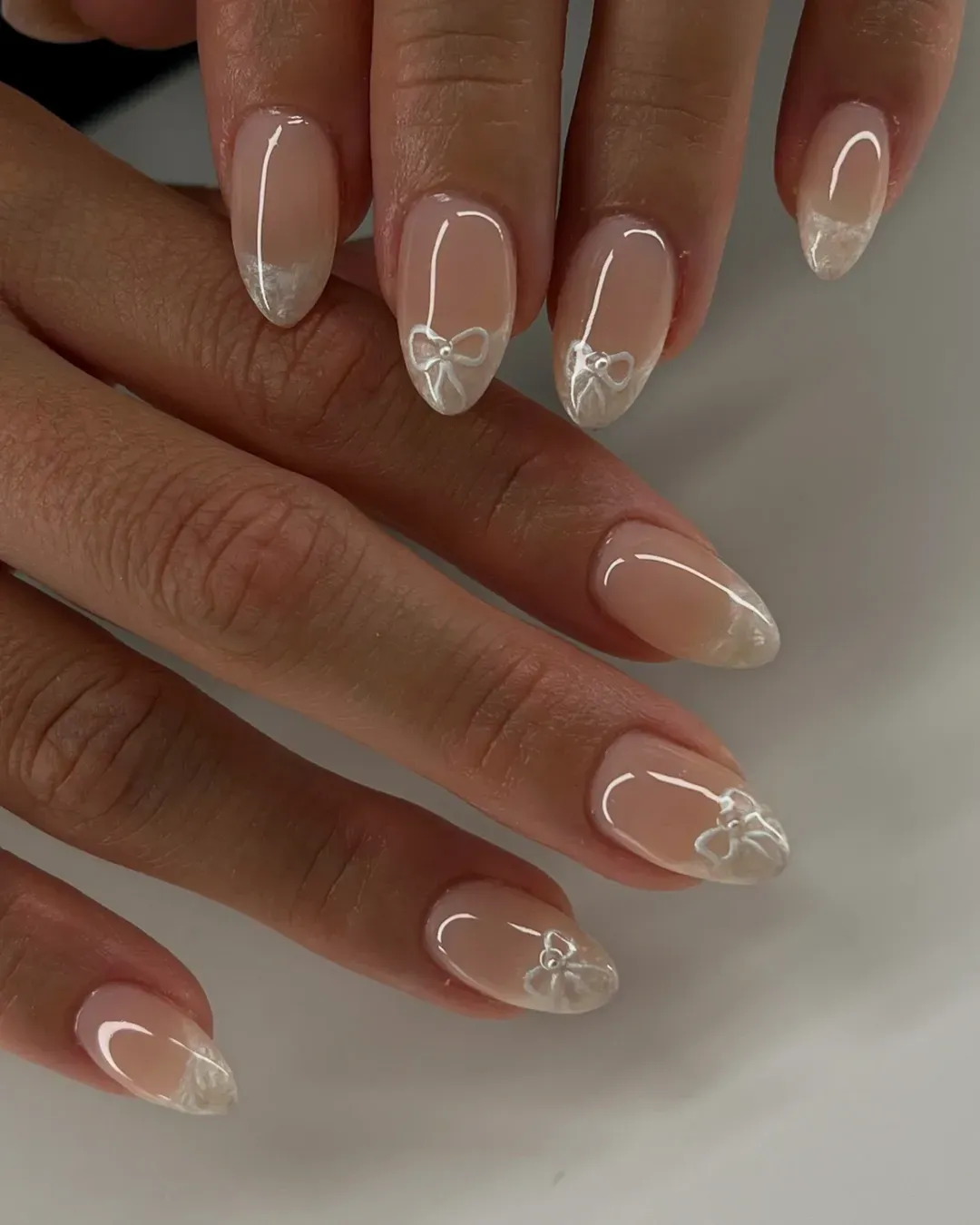 Nude nails with soft white tips and bow details