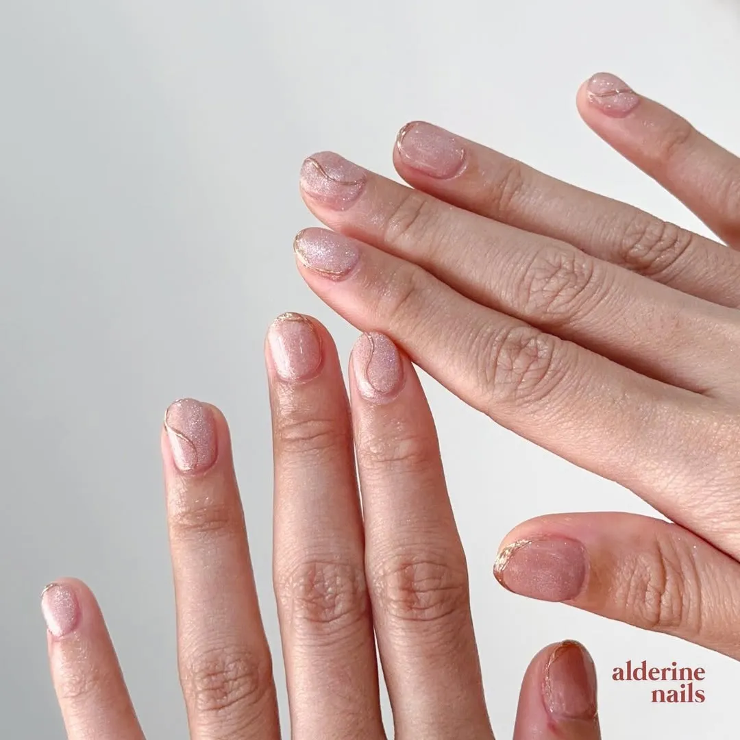 Sheer pink shimmer nails with thin gold curved lines