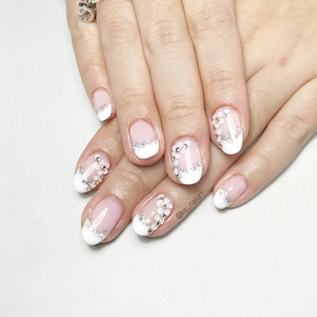 Pink-and-white French tips with silver glitter and floral embellishments